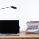 laptop on desk with books and lampshade